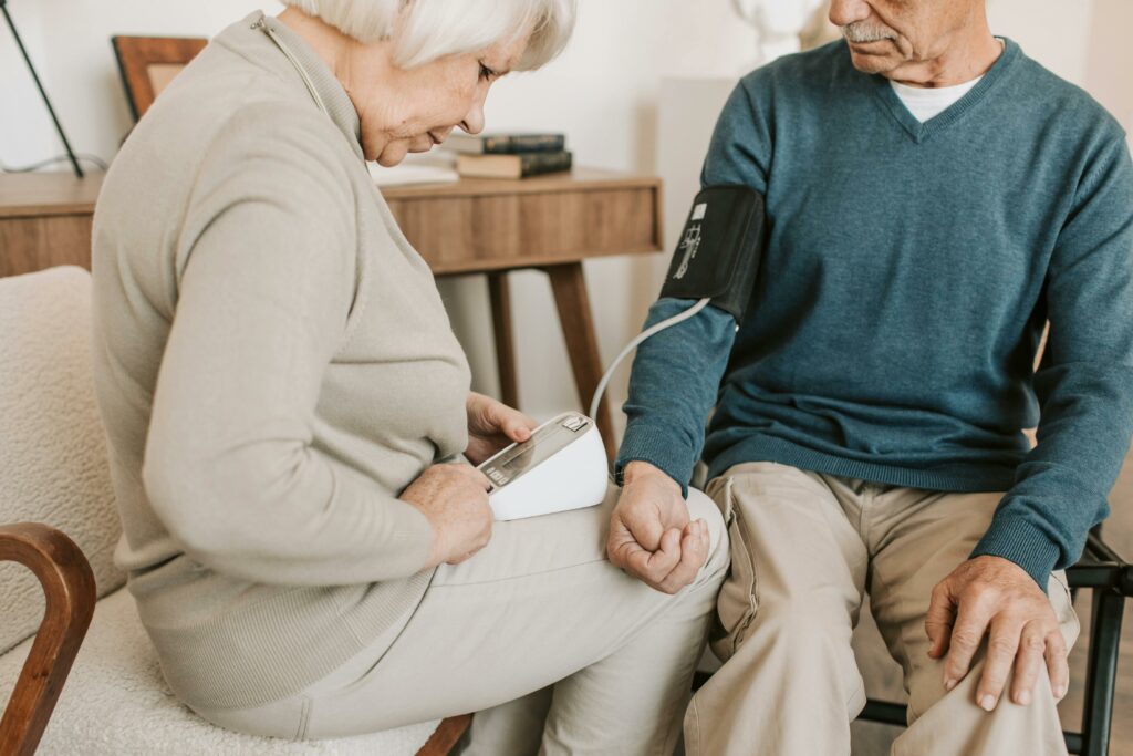 Senior couple at home measuring blood pressure for health check.