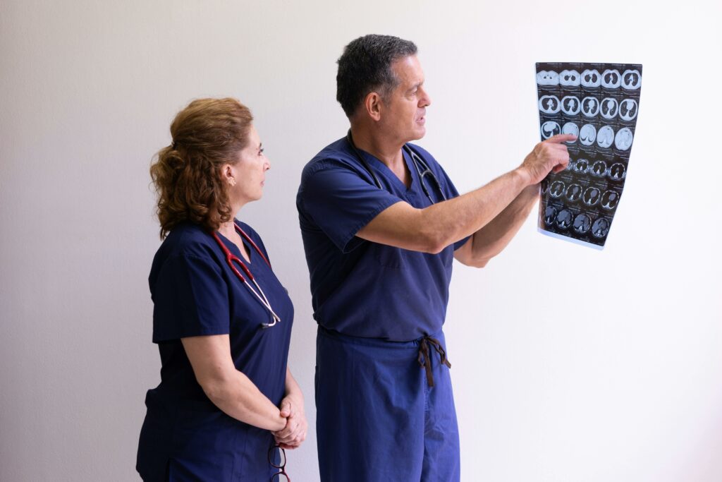 Two healthcare professionals in scrubs examining a medical x-ray image, discussing diagnosis.